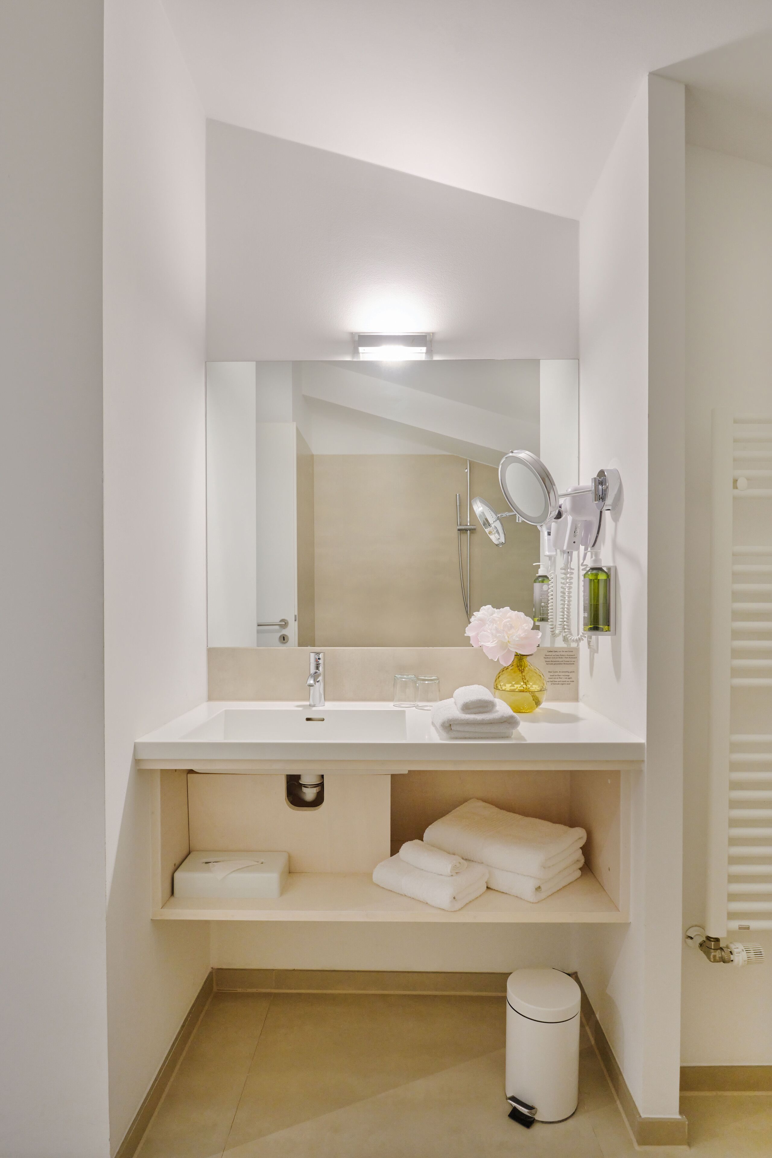 A modern bathroom with a white sink, mirror, and towel rack.