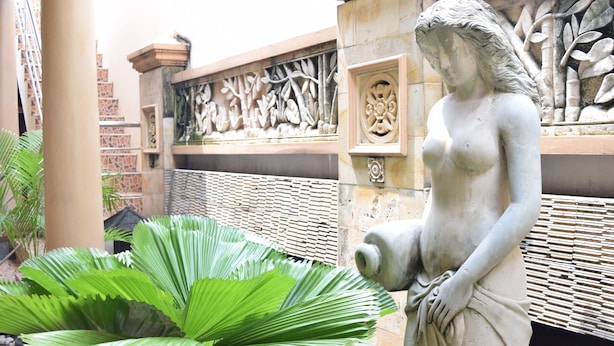 A statue in a courtyard with a large plant in the foreground. - Roemah Canting (Yogyakarta)