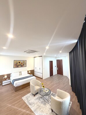 Une chambre d’hôtel avec un lit, un bureau, une chaise, une petite table avec un vase et un tableau au mur.