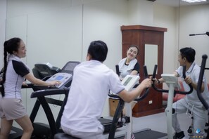 A fitness room with treadmills, stationary bikes, and a mirror. - Vientiane Plaza Hotel (Vientiane)