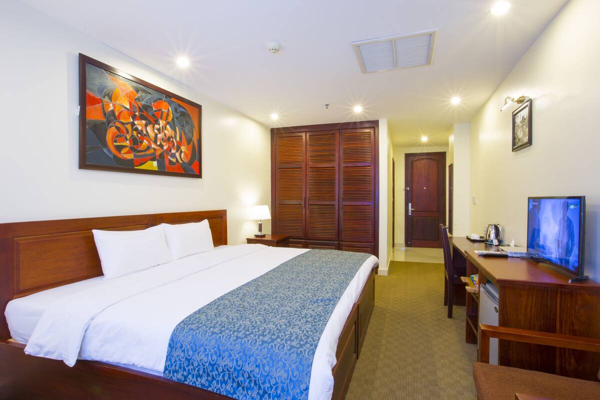 Een hotelkamer met een groot bed, een bureau met een computer, een televisie en een kledingkast.