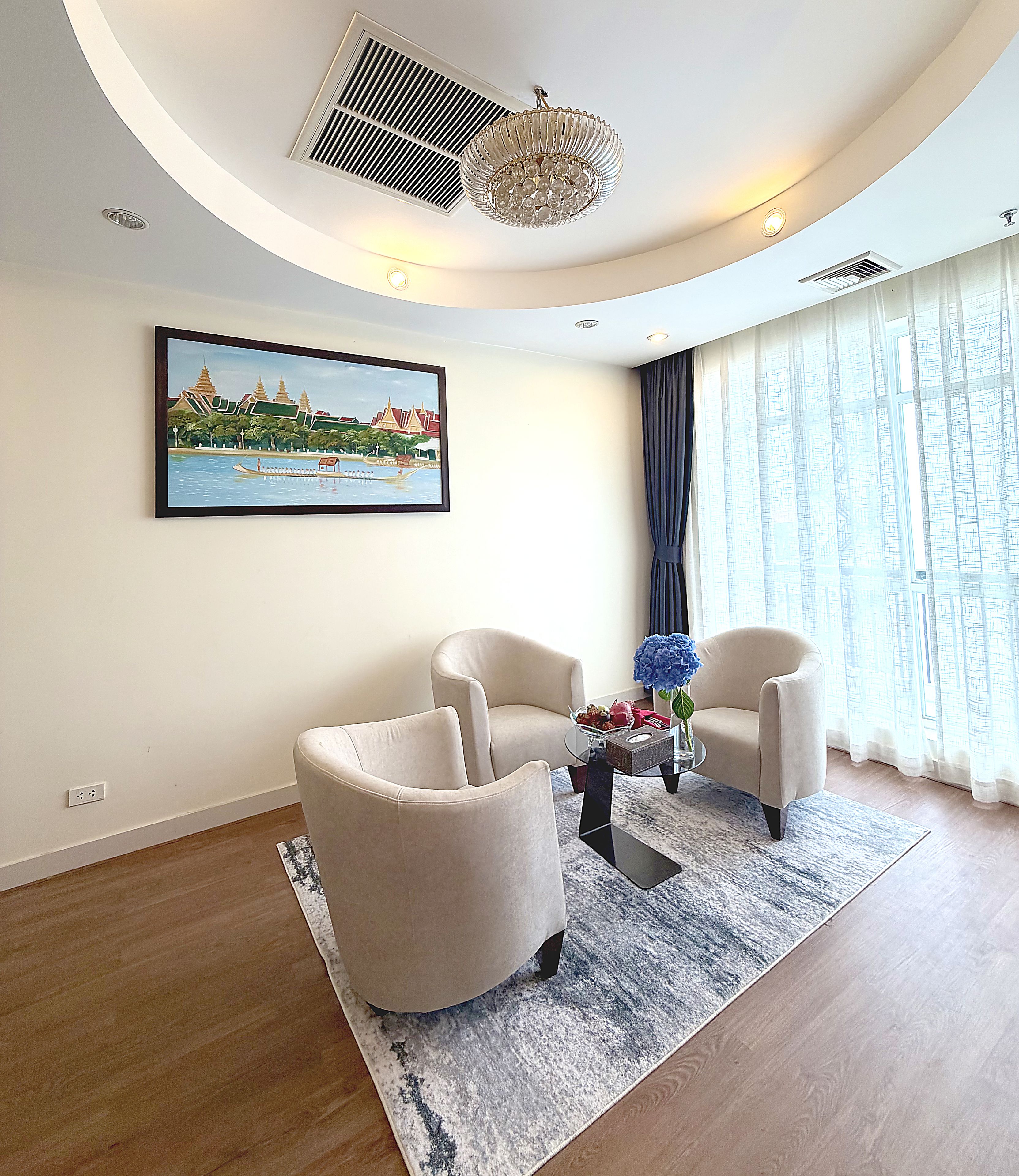 Un salon moderne avec deux fauteuils, une table basse et un tableau représentant un paysage.