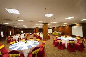 Un salón de banquetes con mesas redondas, sillas rojas y cintas amarillas.