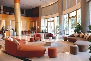 Un hall d’entrée spacieux avec un espace salon central, de grandes fenêtres et un comptoir d’accueil.