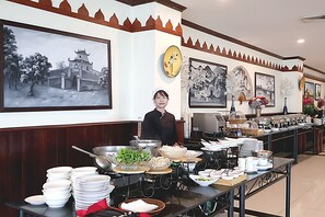 Ein reichhaltiges Buffet mit verschiedenen Speisen und einer Person, die bedient.