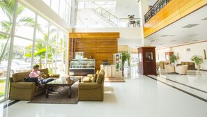 A spacious lobby with a high ceiling, large windows, a central seating area, and a staircase leading to an upper level. - Vientiane Plaza Hotel (Vientiane)