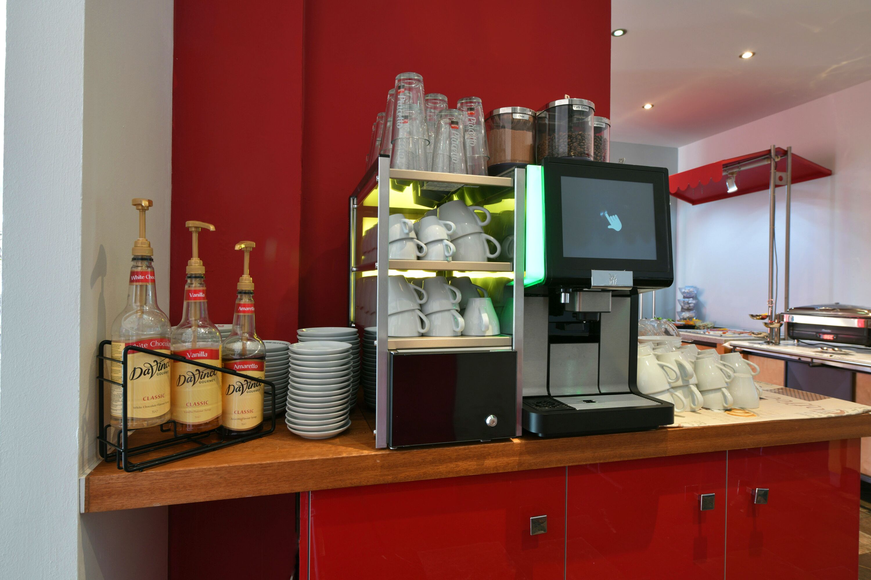 A coffee station with a coffee machine, cups, and bottles of coffee.