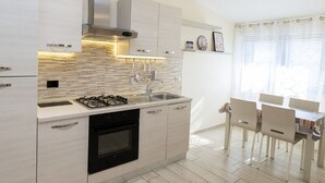 Une cuisine moderne équipée d’une cuisinière à gaz, d’un évier et d’un coin repas avec une table et des chaises.