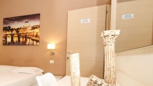 Une chambre d’hôtel avec un lit, une table de chevet, une lampe, un tableau représentant un paysage urbain et un miroir.