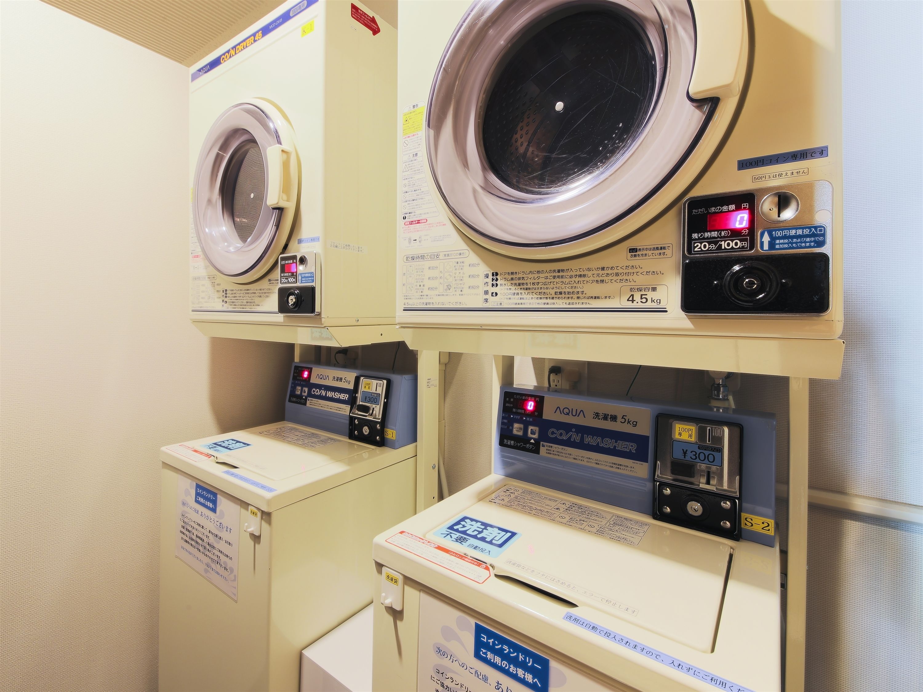 Een wasserette met meerdere wasmachines en drogers, elk met bedieningspanelen en instructies.