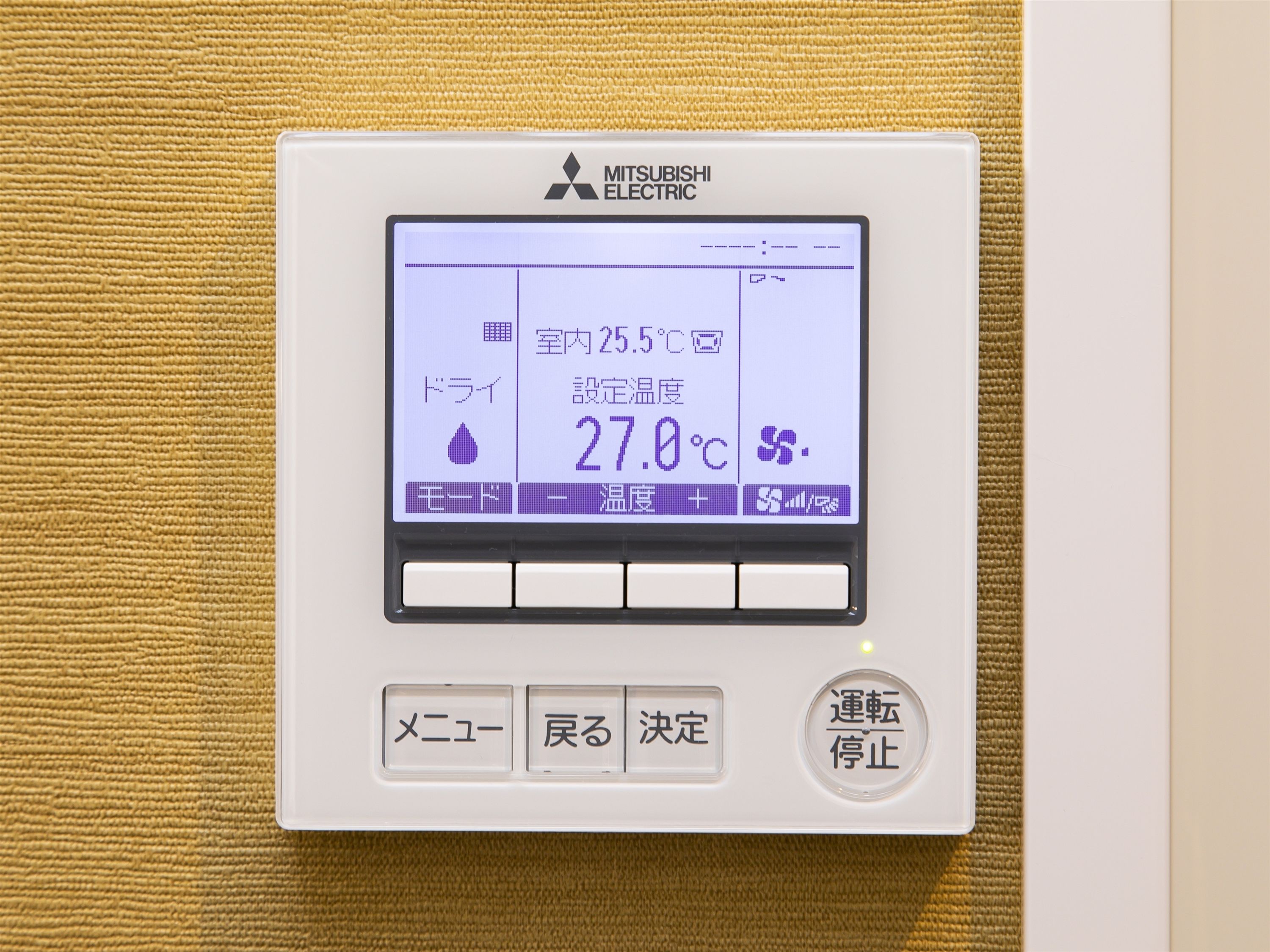 A Mitsubishi Electric thermostat with a digital display, buttons, and a control panel.