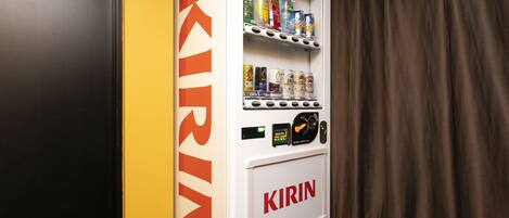 Un distributeur automatique arborant la marque « KIRIN », situé dans une pièce dont la porte est noire et le mur jaune.