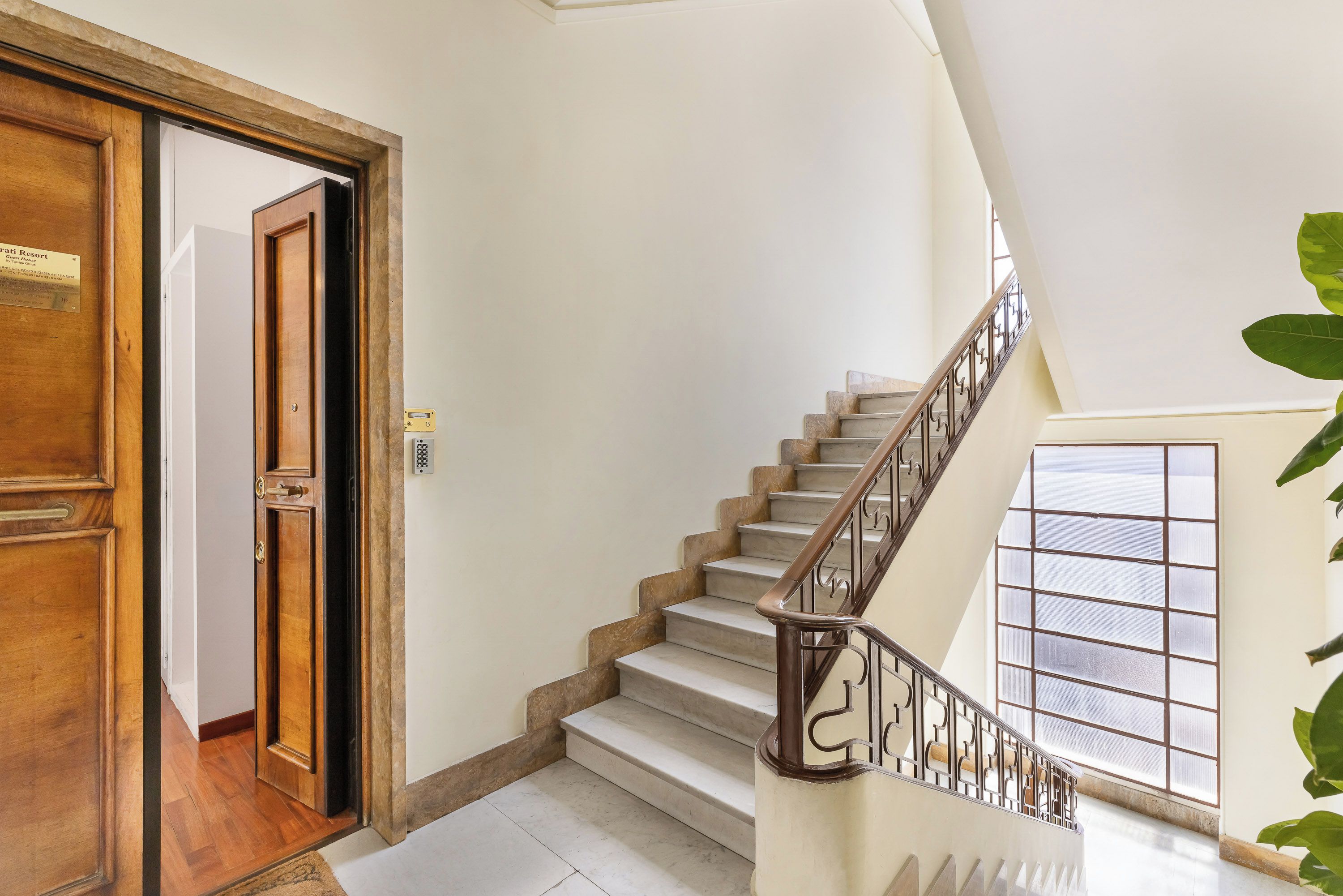A staircase with a wooden handrail and a view of a room with a wooden door.