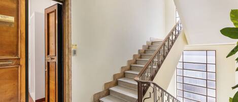 Una escalera con barandilla de madera y vista a una habitación con puerta de madera.