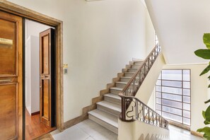 A staircase with a wooden handrail and a view of a room with a wooden door. - Torripa Collection - Domus Vittoria - Prati (Rome)