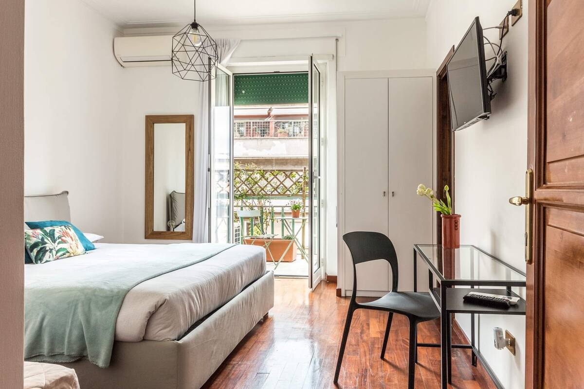 A bedroom with a bed, a desk, a chair, and a TV.