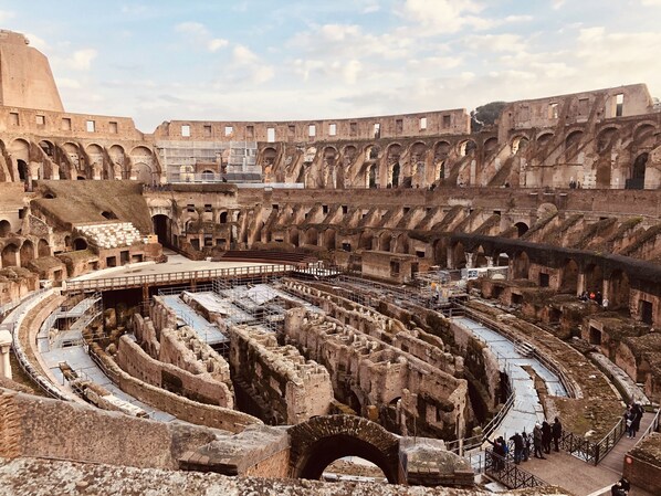 An ancient amphitheater with multiple levels of seating and a central stage area.