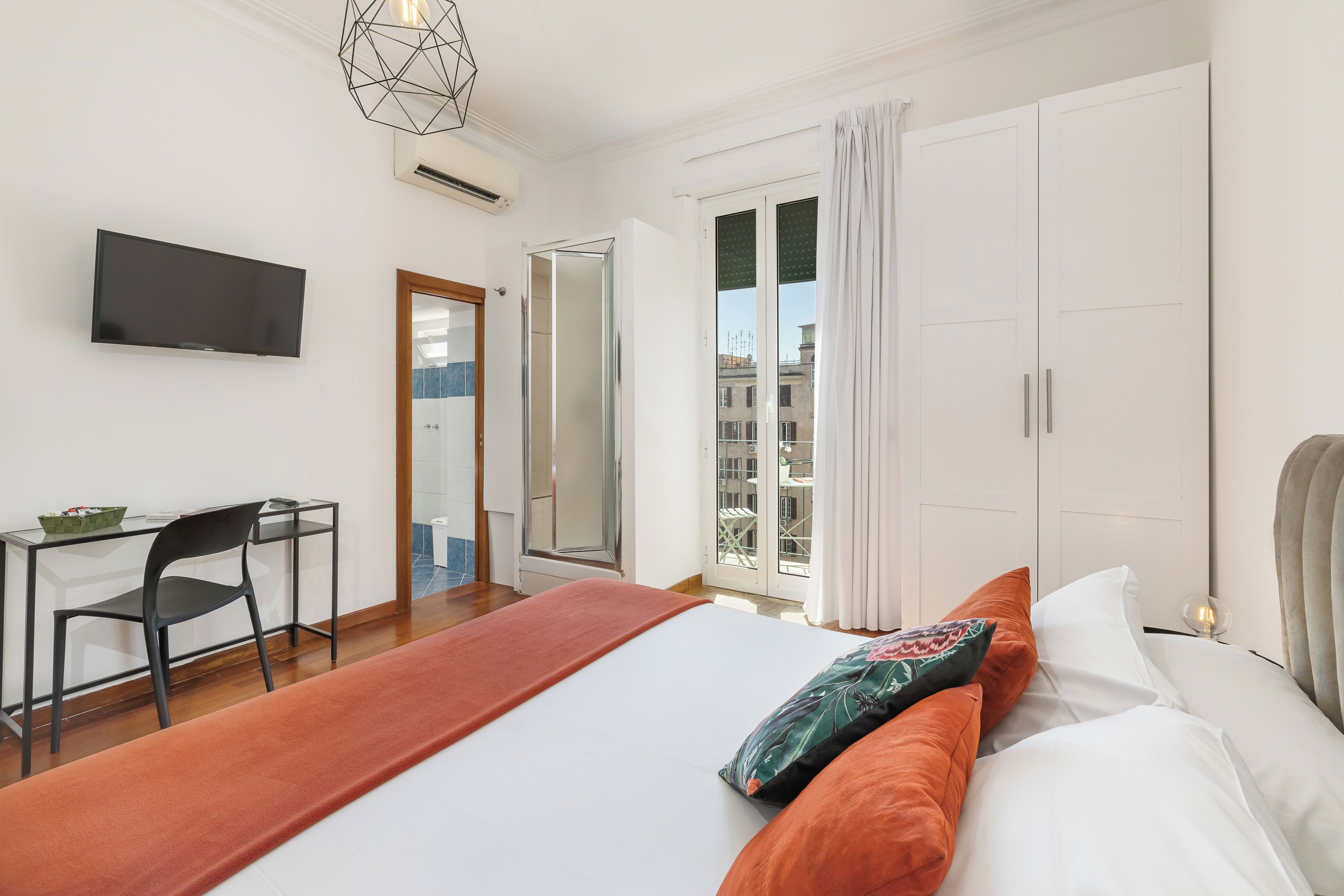 A hotel room with a bed, a desk, a chair, a television, and a window with curtains.