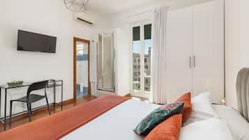 Habitación de hotel con una cama, un escritorio, una silla, un televisor y vistas a la ciudad desde la ventana.