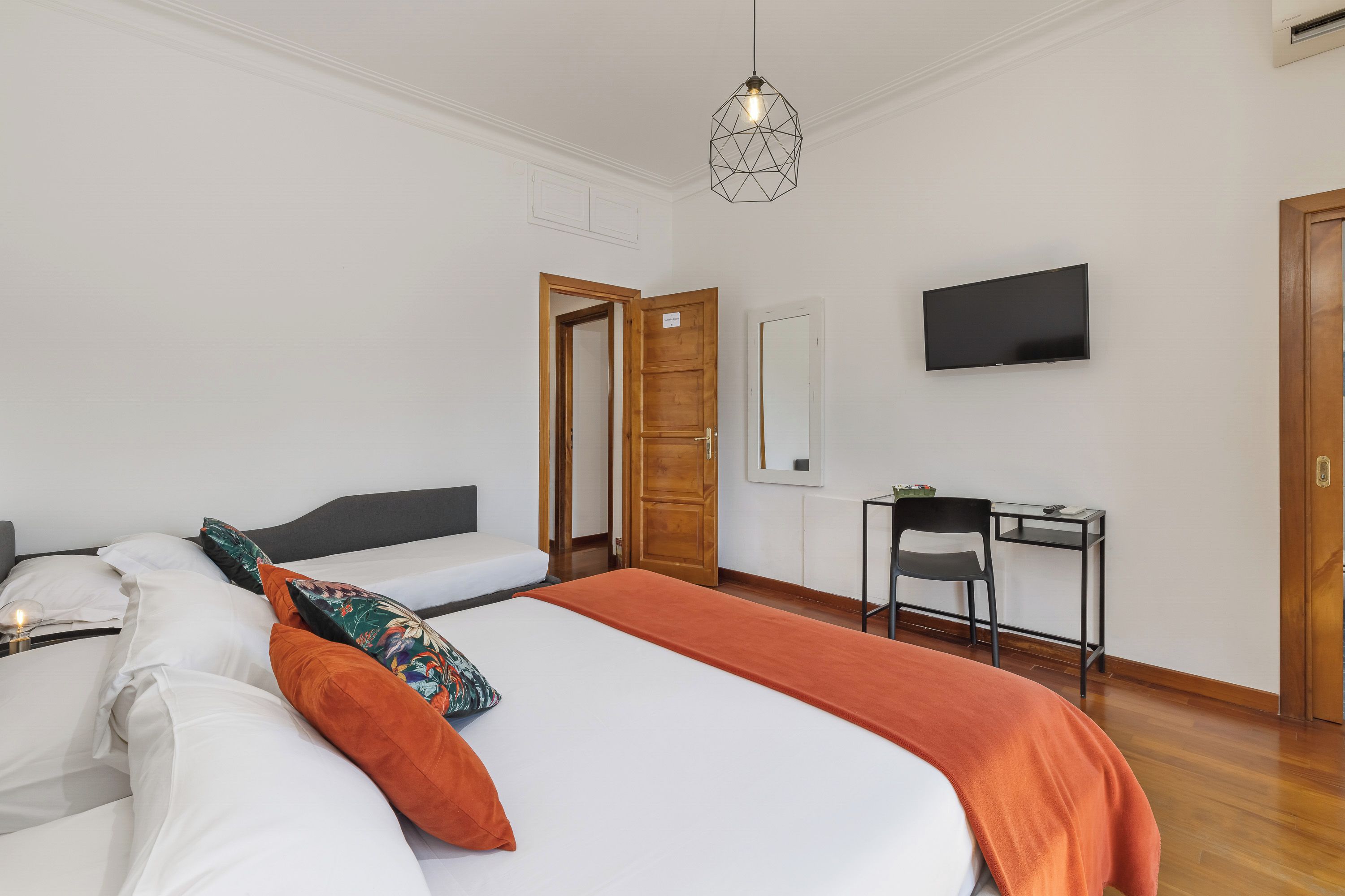 Una habitación de hotel con una cama, un escritorio, un televisor y una puerta.