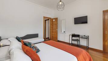 Una habitación de hotel con una cama, un escritorio, un televisor y una puerta.