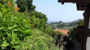 A view of a hillside with a building featuring a red-tiled roof. - Bisalde Agroturismo (Bakio)
