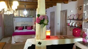 A cozy bedroom with a bed, bedside table, and a nightstand. There is a chandelier, a vase with flowers, and a lamp on the nightstand. - Bisalde Agroturismo (Bakio)