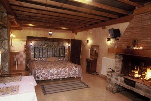 A cozy bedroom with a bed, a stone fireplace, and a stone wall. - Bisalde Agroturismo (Bakio)
