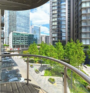 A modern urban hotel with a glass balcony overlooking a parking area and a river.
