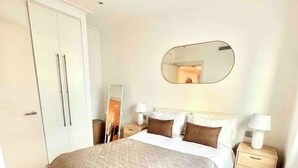 Un dormitorio con cama, mesitas de noche, armario y espejo.