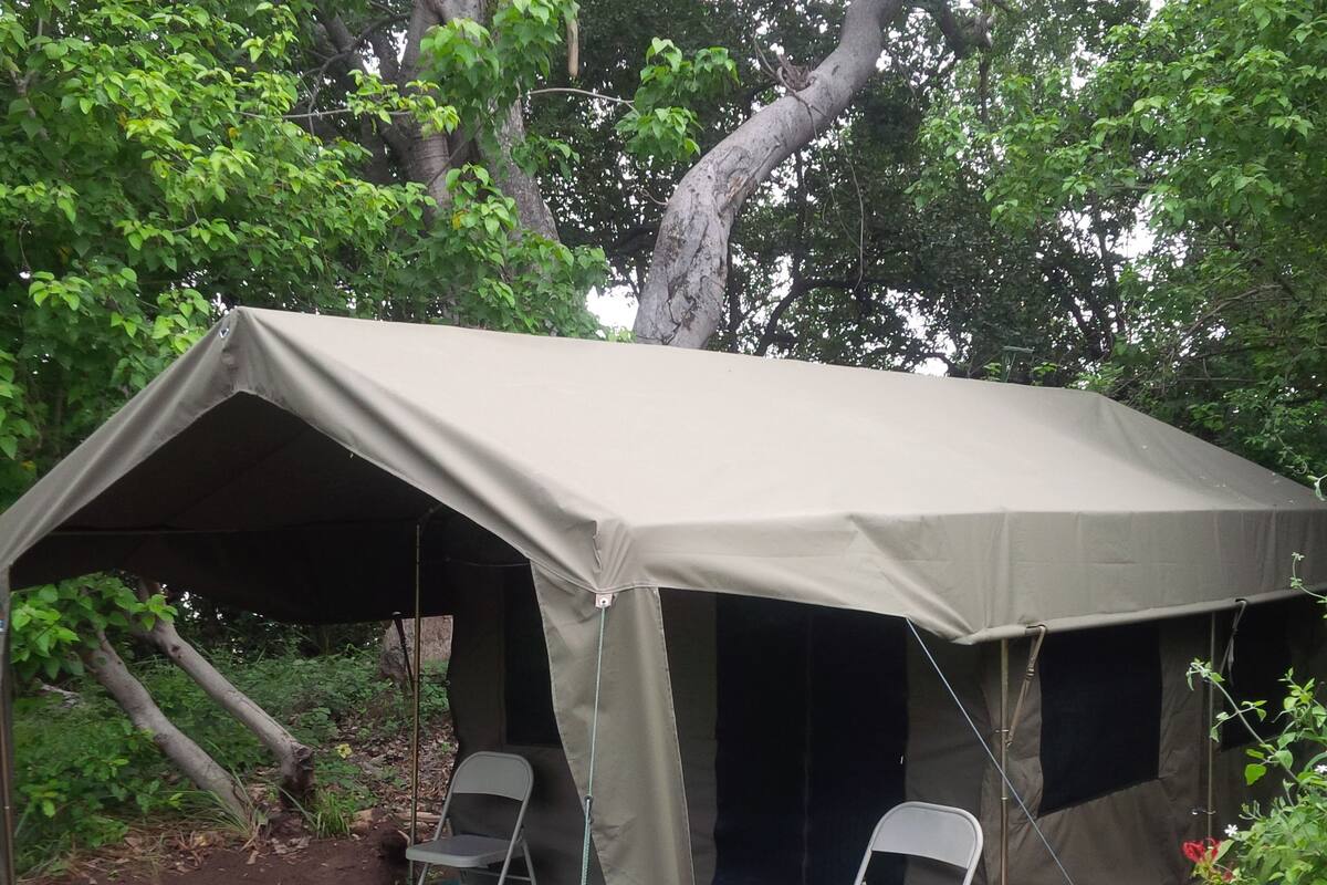 A tent with two chairs and a green mat.