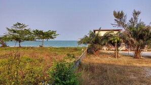 A coastal property with a view of the sea, surrounded by greenery and a building with a red roof. - Bamboo Resort (Khanom)