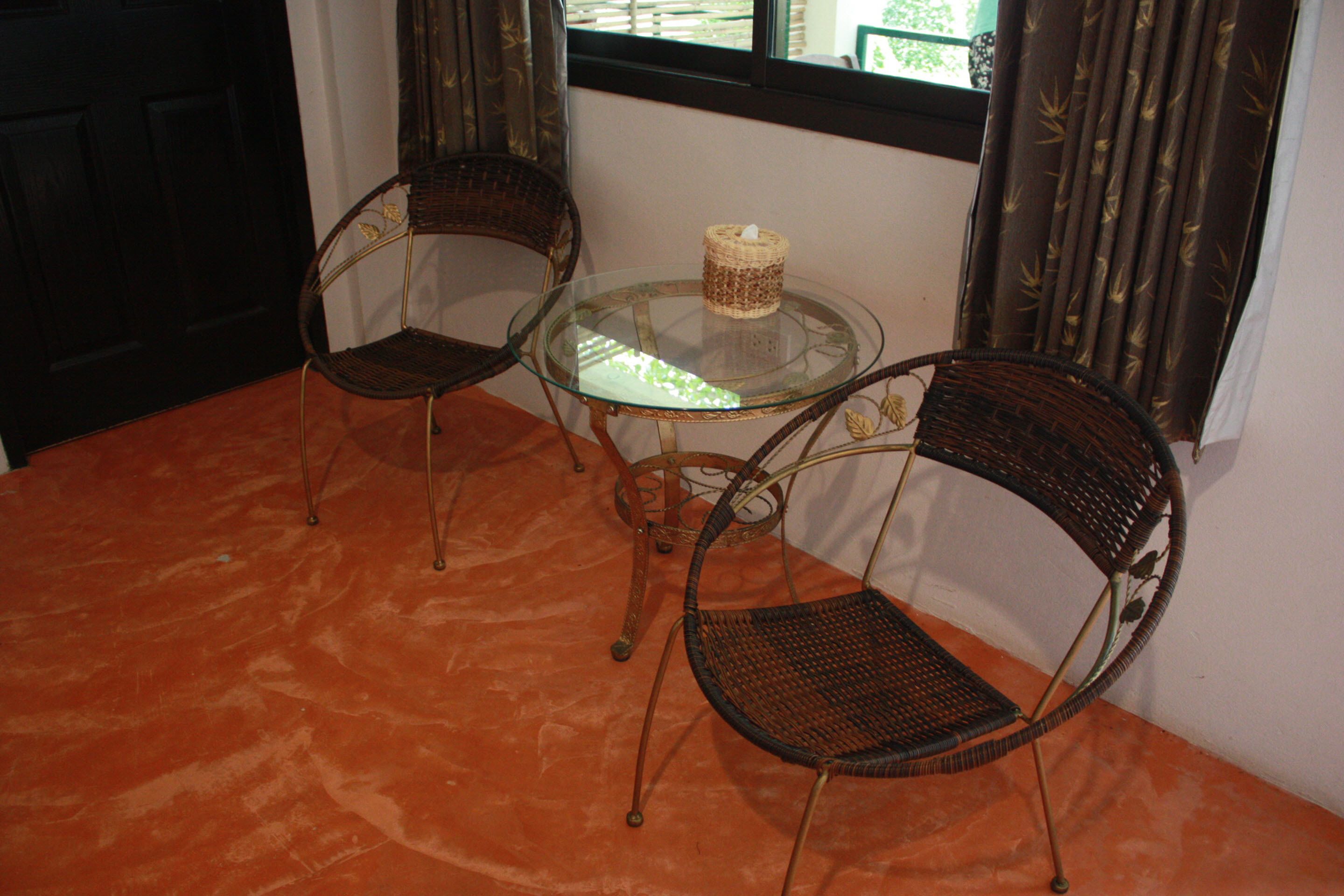 A room with two wicker chairs and a glass table.