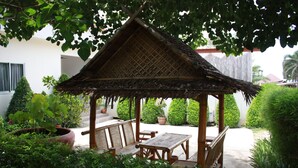 A wooden gazebo with a thatched roof, surrounded by potted plants and a wooden table and chairs. - Bamboo Resort (Khanom)