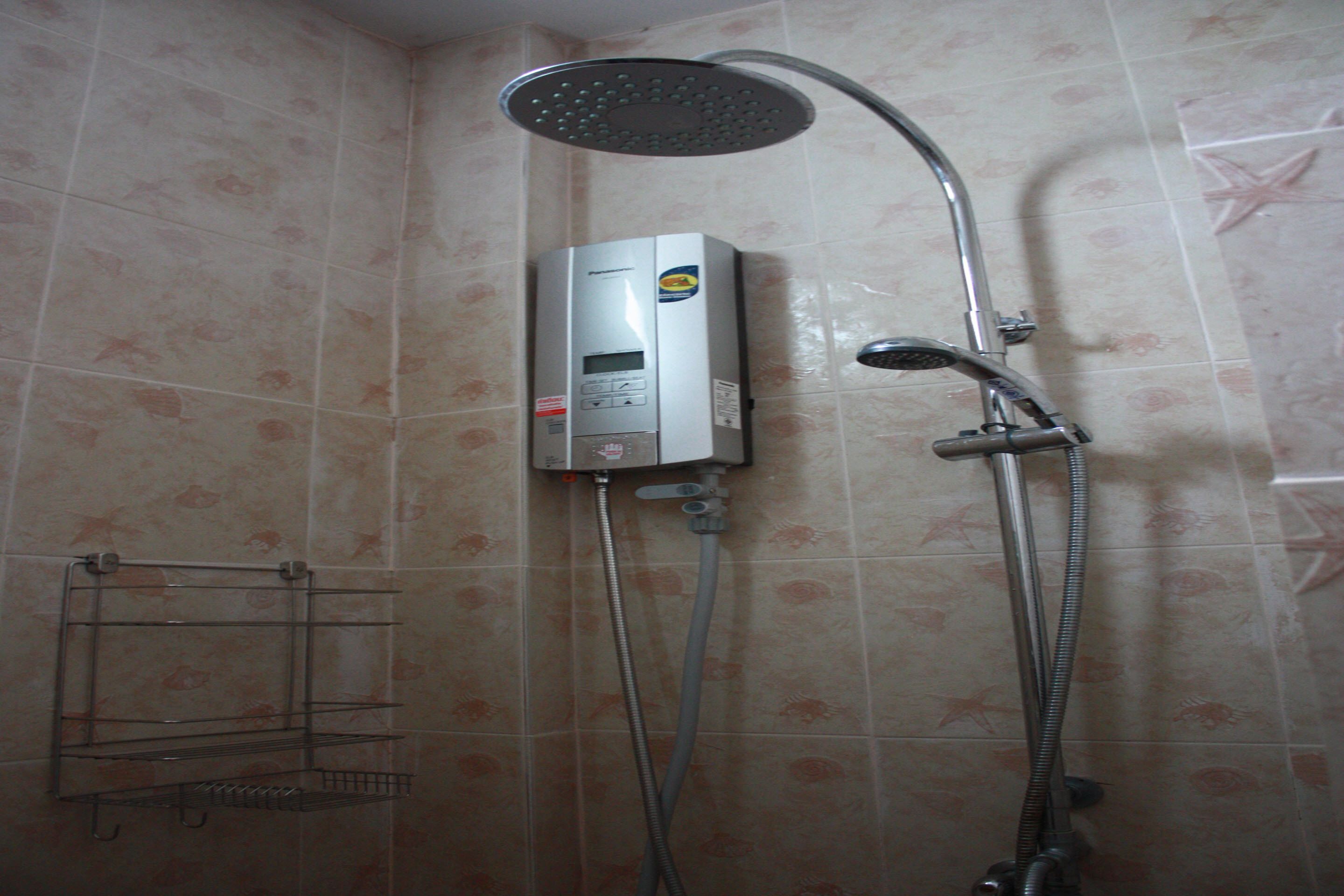 A bathroom with a shower, a wall-mounted heater, and a towel rack.