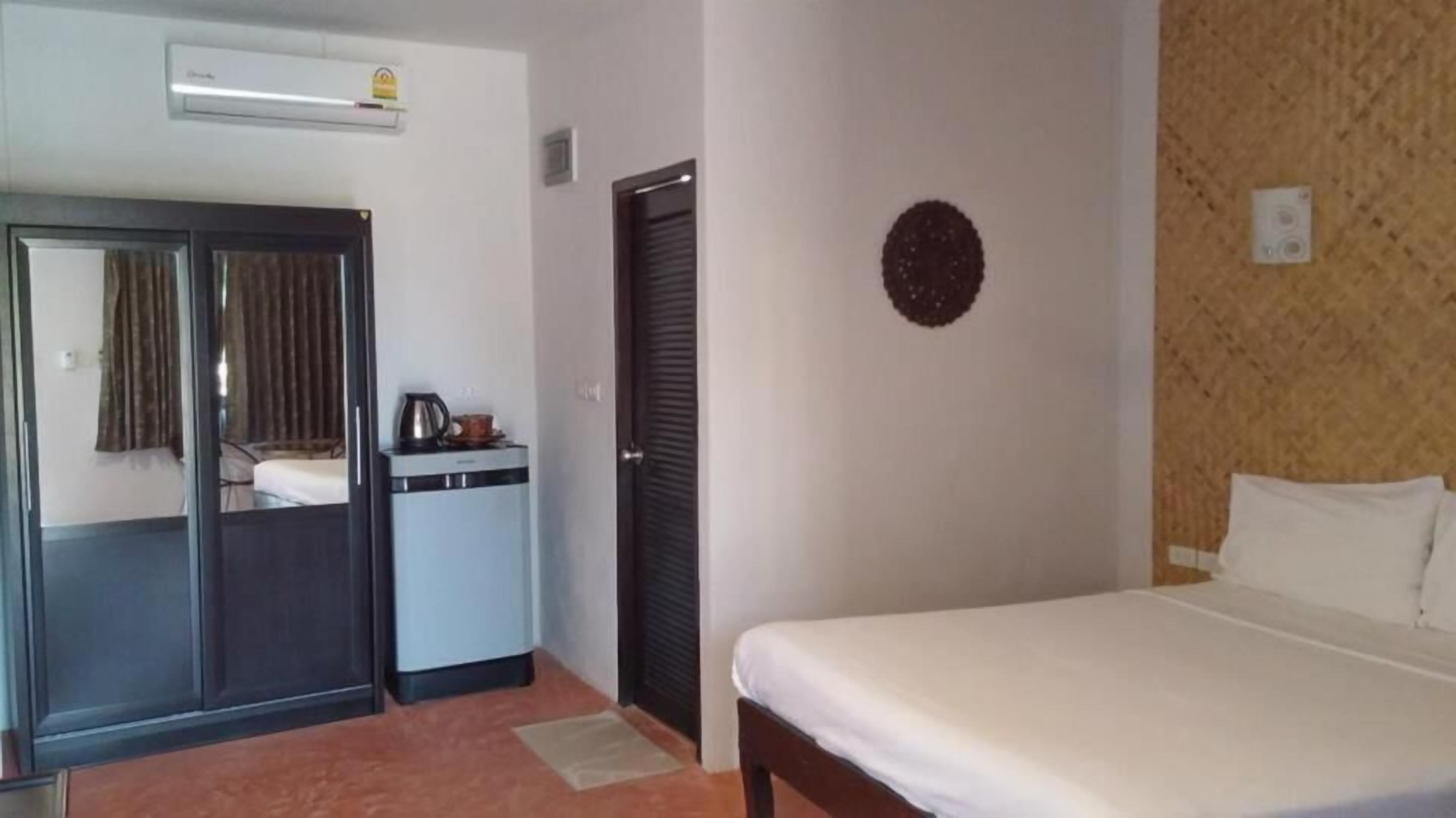 A hotel room with a bed, a wardrobe, a small kitchenette, and a door.