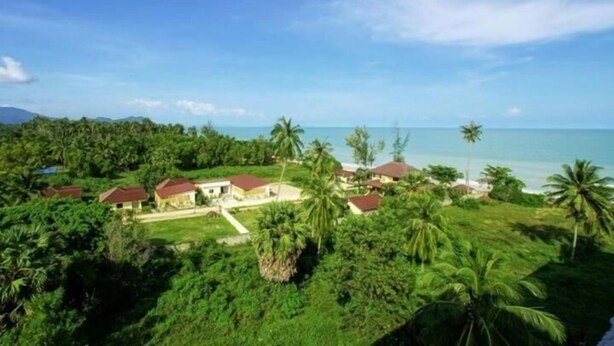 A coastal property with multiple houses surrounded by lush greenery and palm trees, overlooking the ocean. - Bamboo Resort (Khanom)
