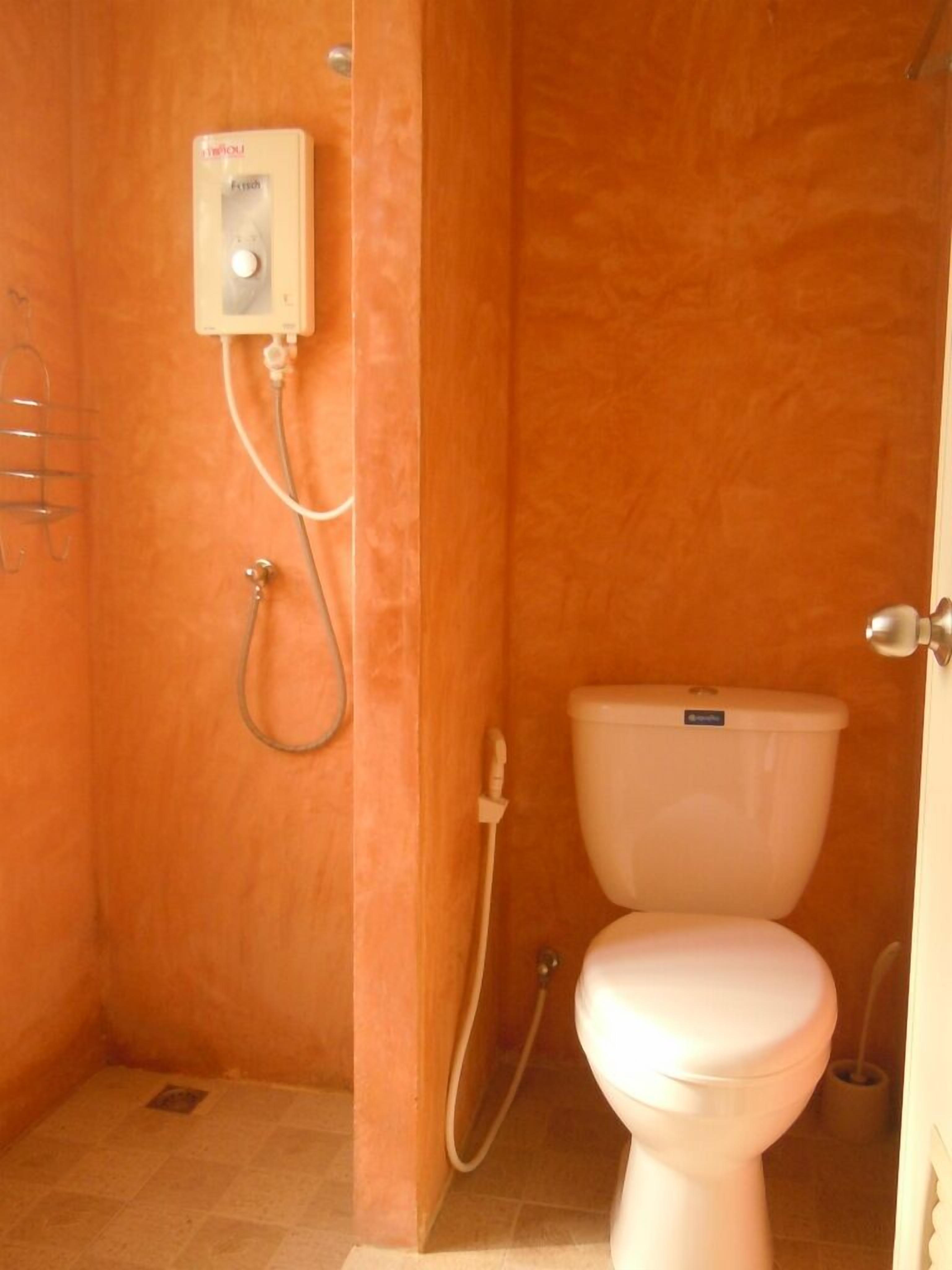 A bathroom with a toilet, a shower, and a hand dryer.