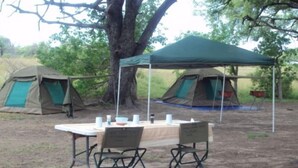 A campsite with two tents, a table with chairs, and a green canopy. - South Mobile Camp (Nxai Pan National Park)