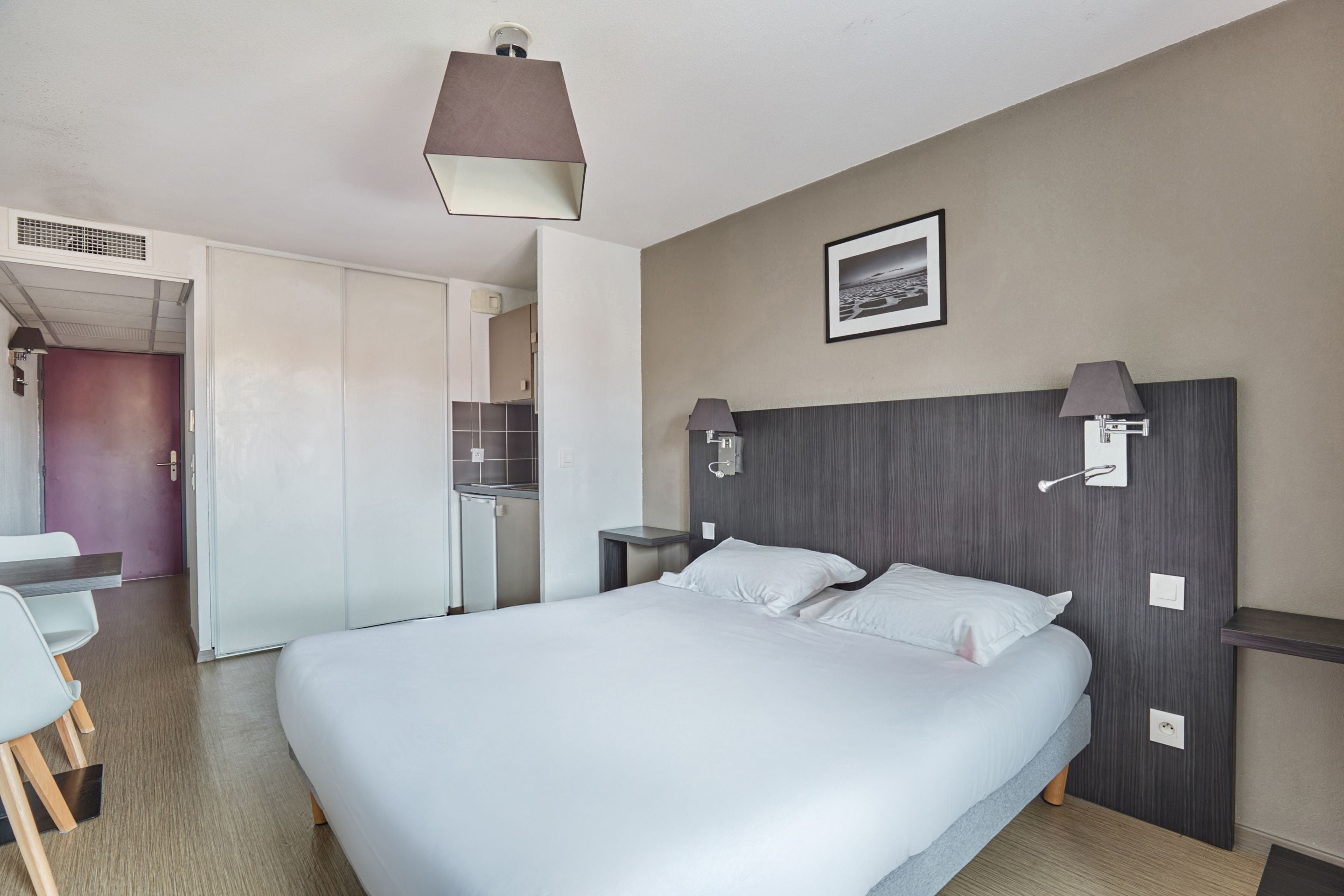 Una habitación de hotel moderna con una cama grande, un escritorio y una kitchenette.
