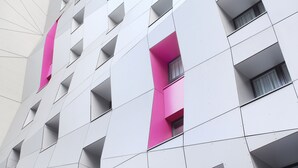 Ein modernes Gebäude mit einer geometrischen Fassade und mehreren Balkonen.