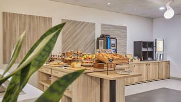 Zona de desayuno tipo buffet con diversas opciones de comida y una máquina de café.