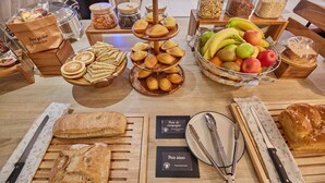 Ein reichhaltiges Buffet mit verschiedenen Speisen, darunter Brot, Gebäck, Früchte und Nüsse.