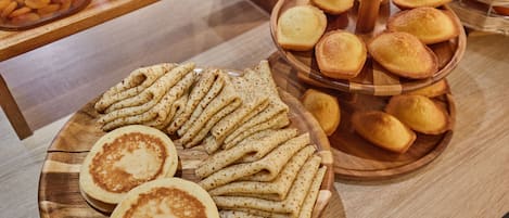 A wooden table with a variety of baked goods, including pancakes and pastries.