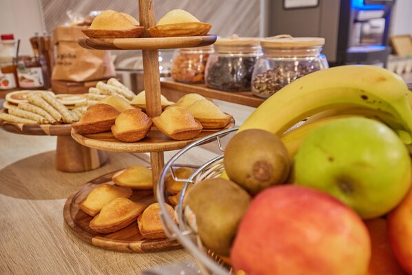 Una mesa de buffet con varios productos horneados y frutas frescas.