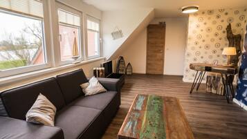 Una sala de estar moderna con sofá, mesa de centro y comedor con mesa y sillas.
