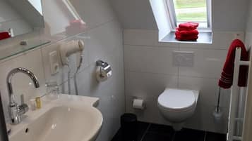 A modern bathroom with a white sink, a toilet, and a small window with a view of the outdoors.
