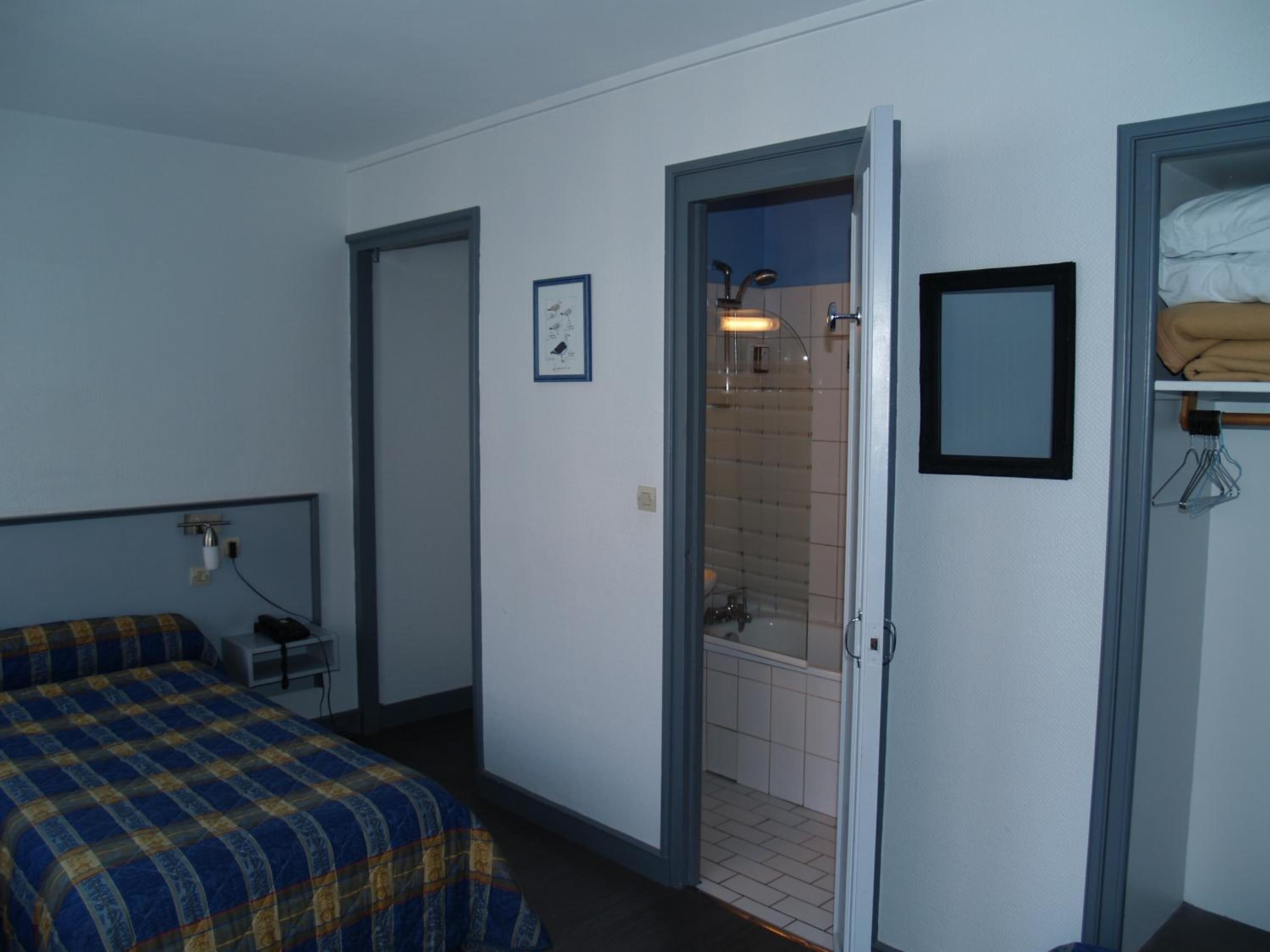 Une chambre avec un lit, une salle de bain avec une douche et une petite table.