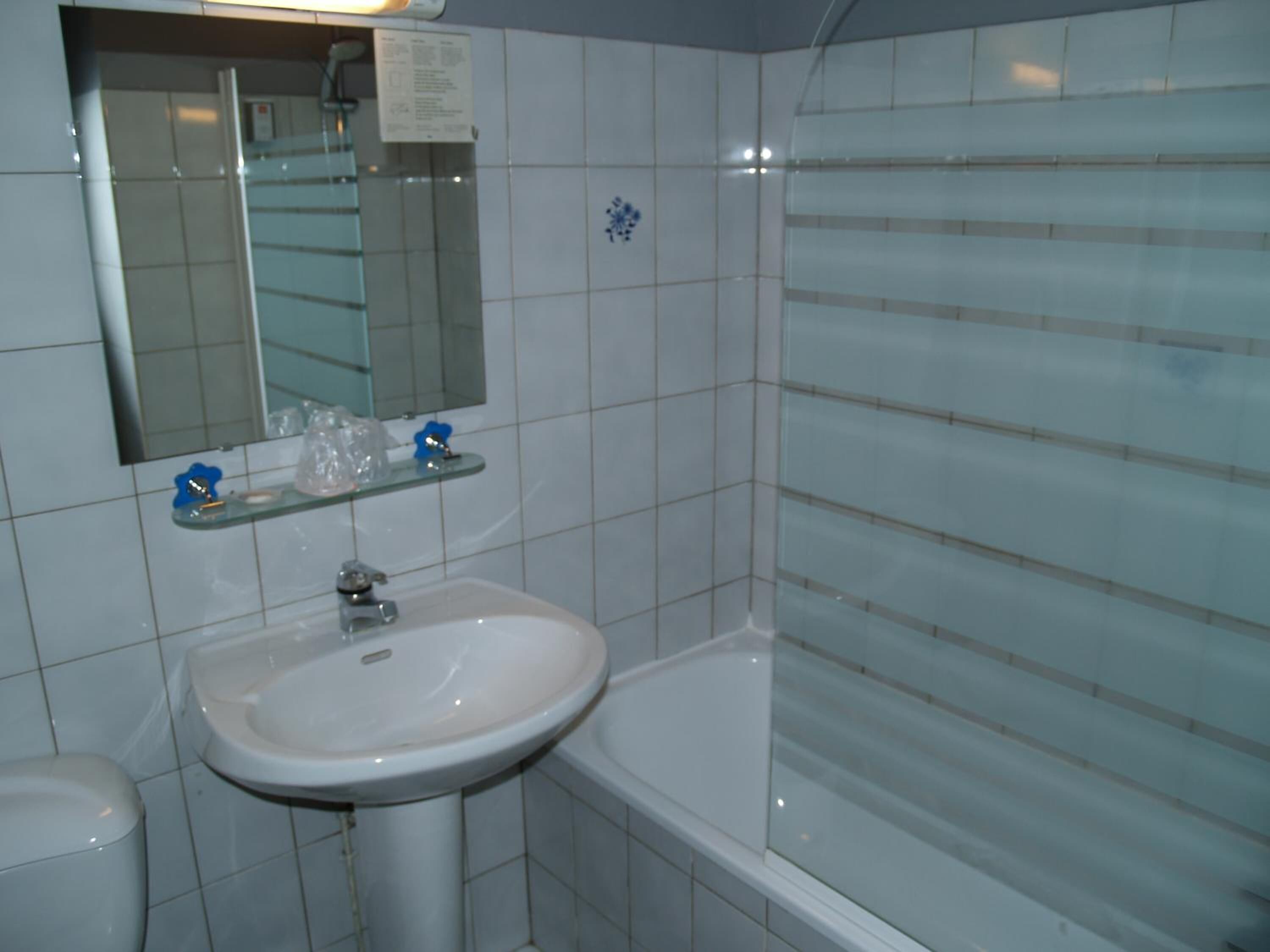Een badkamer met een wit wastafelmeubel, een spiegel en een douchecabine met glazen wanden.