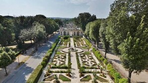 A formal garden with symmetrical pathways and a central fountain, surrounded by trees and a classical building in the background. - Vatican Relais Rome (Rome)
